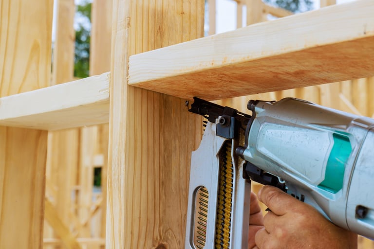 Skilled laborer operates air nail gun to secure wooden beams in construction site during works day